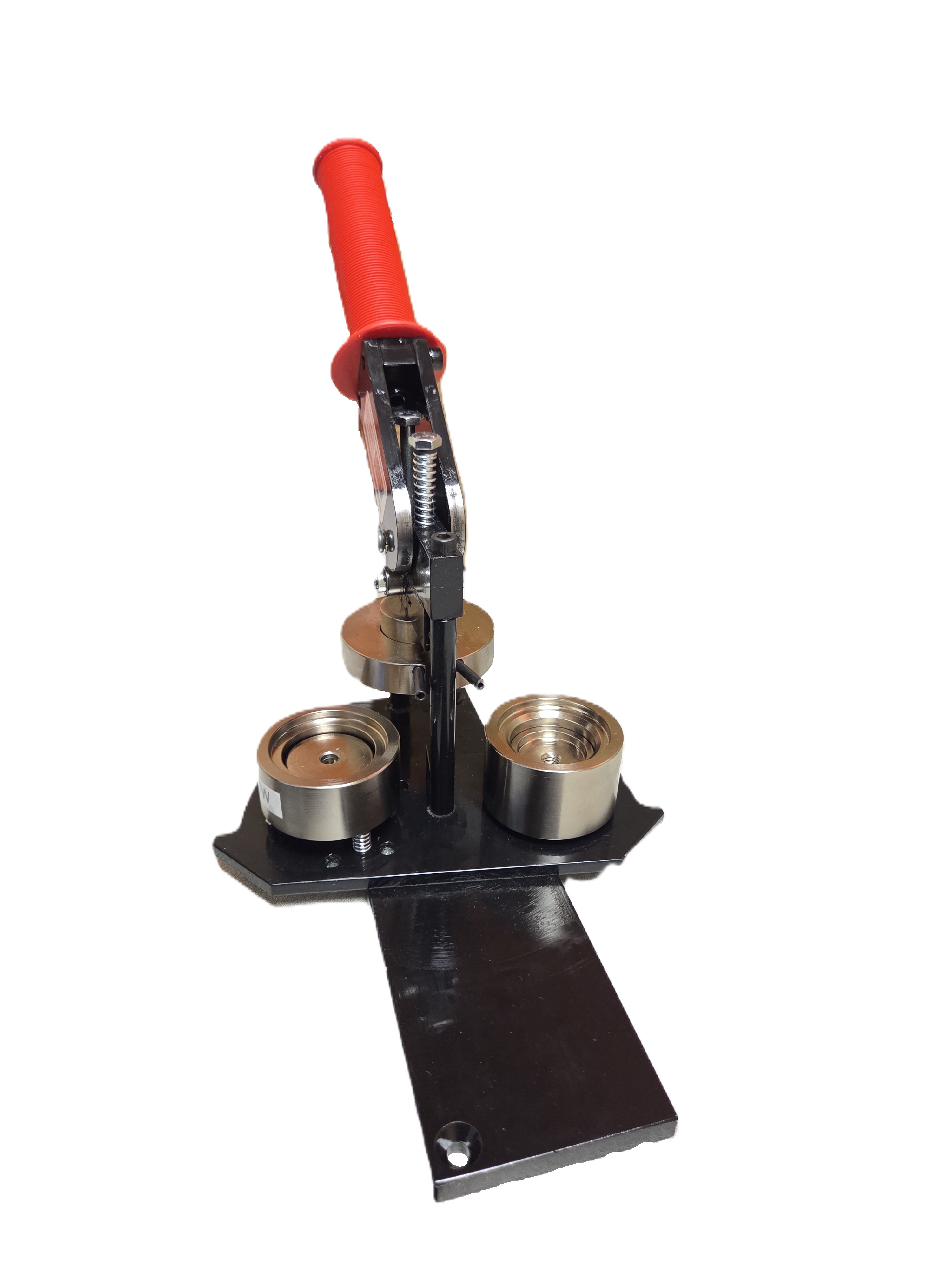 A black metal button maker machine with a red handle.