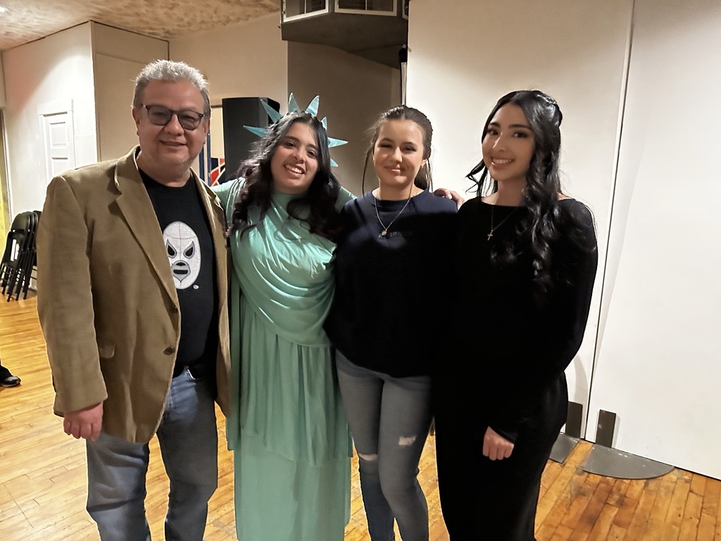 Four participants pose together at Side Street Studio Arts’ production Identity Play. One participant is dressed as the Statue of Liberty, representing themes of culture, identity, and self-expression explored during the community arts event.